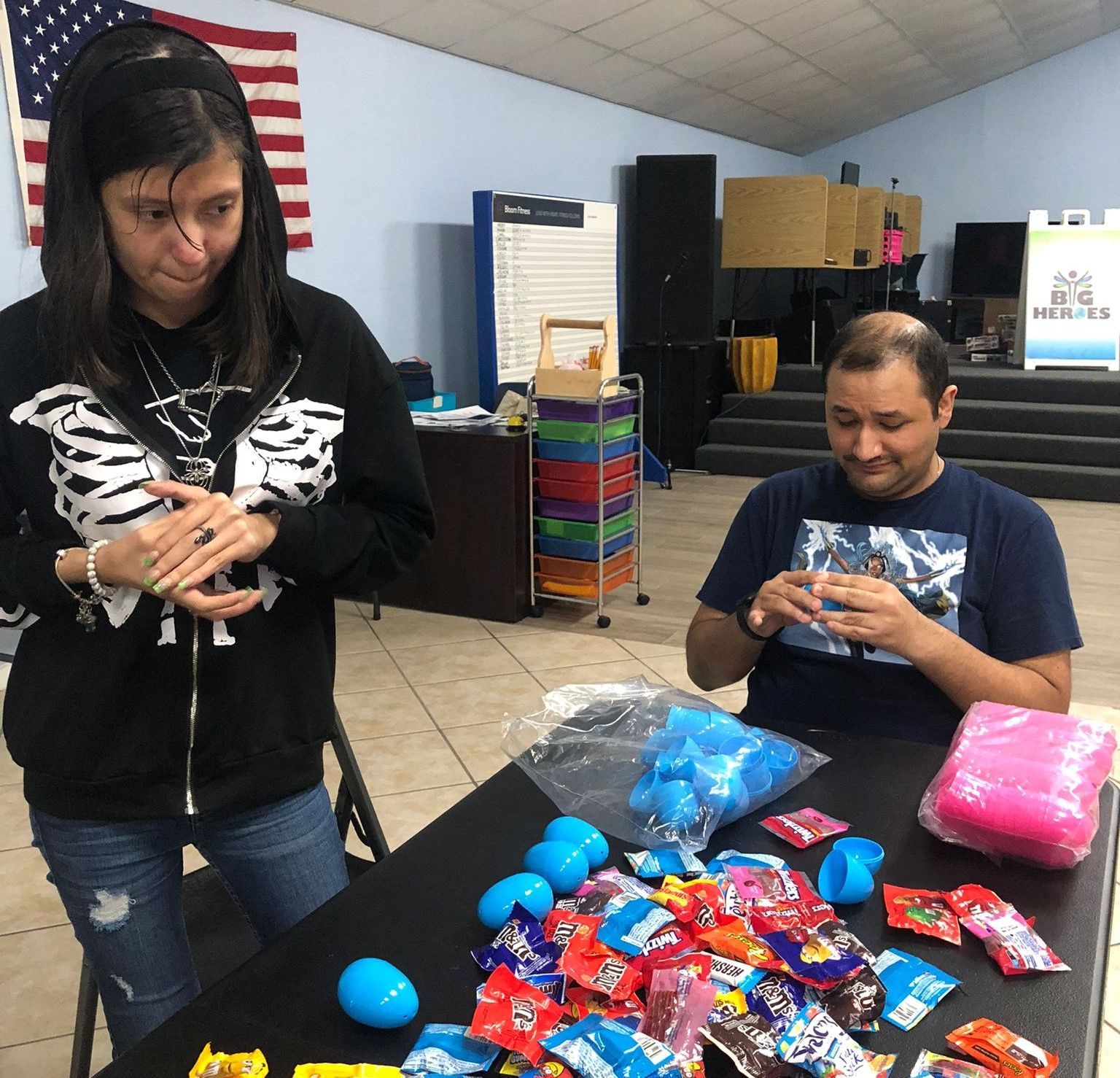 A man and a woman are sitting at a table full of candy
