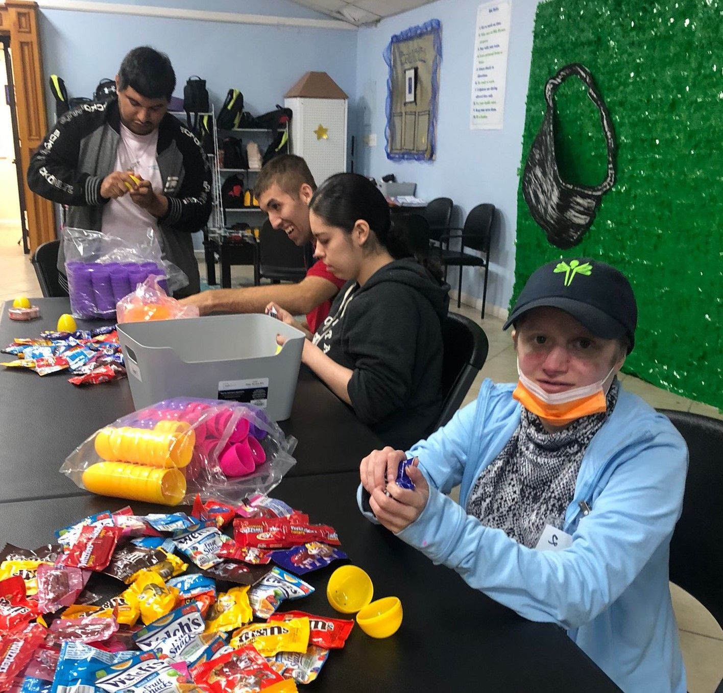 A group of people are sitting around a table with candy on it
