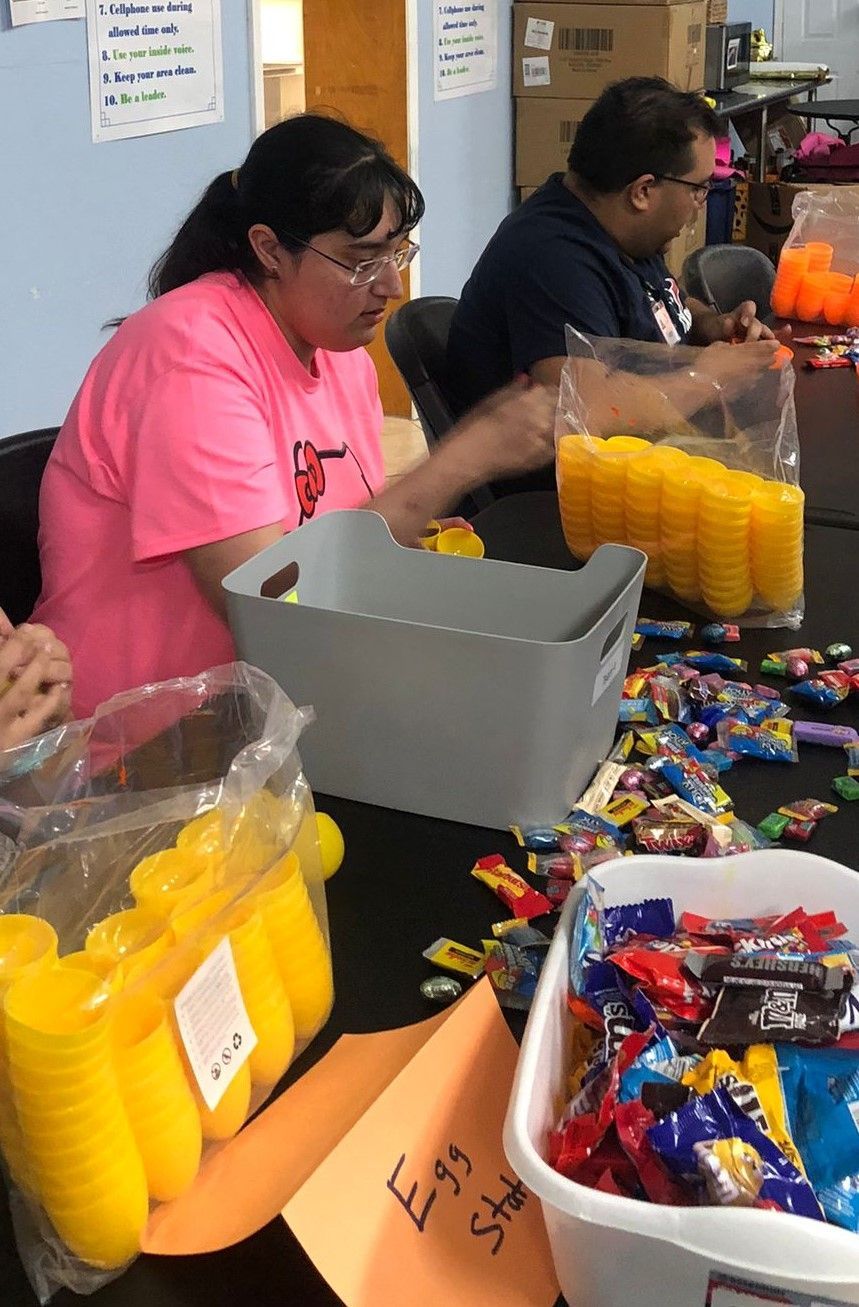 A woman in a pink shirt is sitting at a table filled with candy.