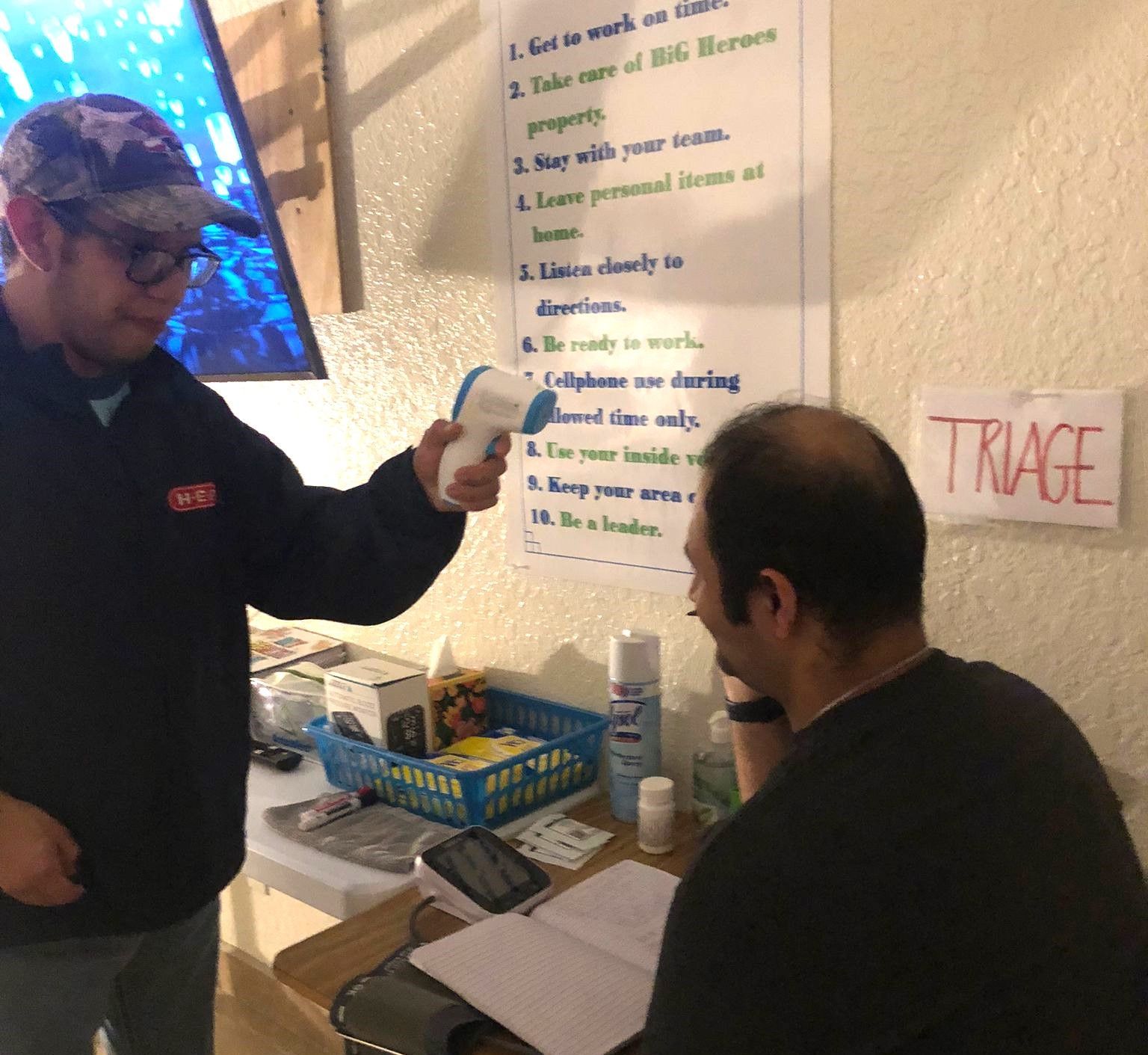 Two men are standing in front of a sign that says triage
