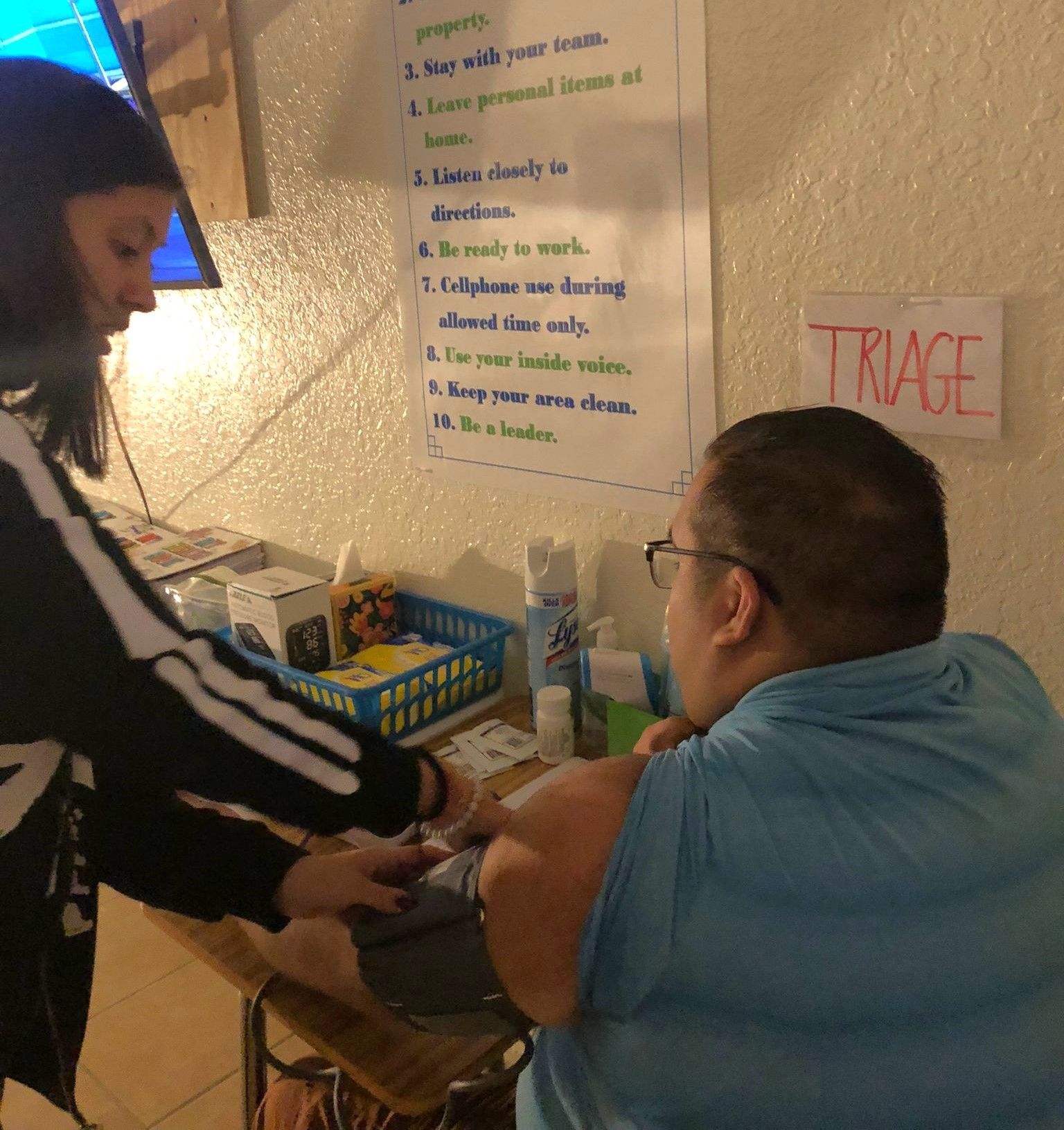 A man is getting an injection from a woman in front of a sign that says triage