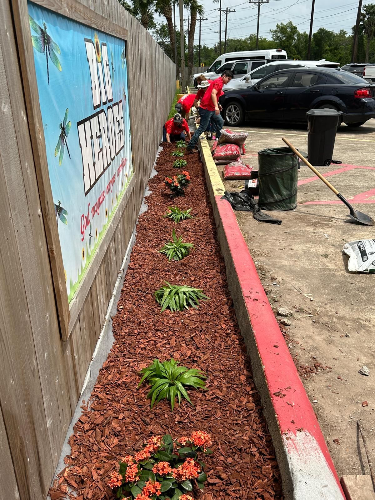 A group of people are working on a garden in a parking lot.