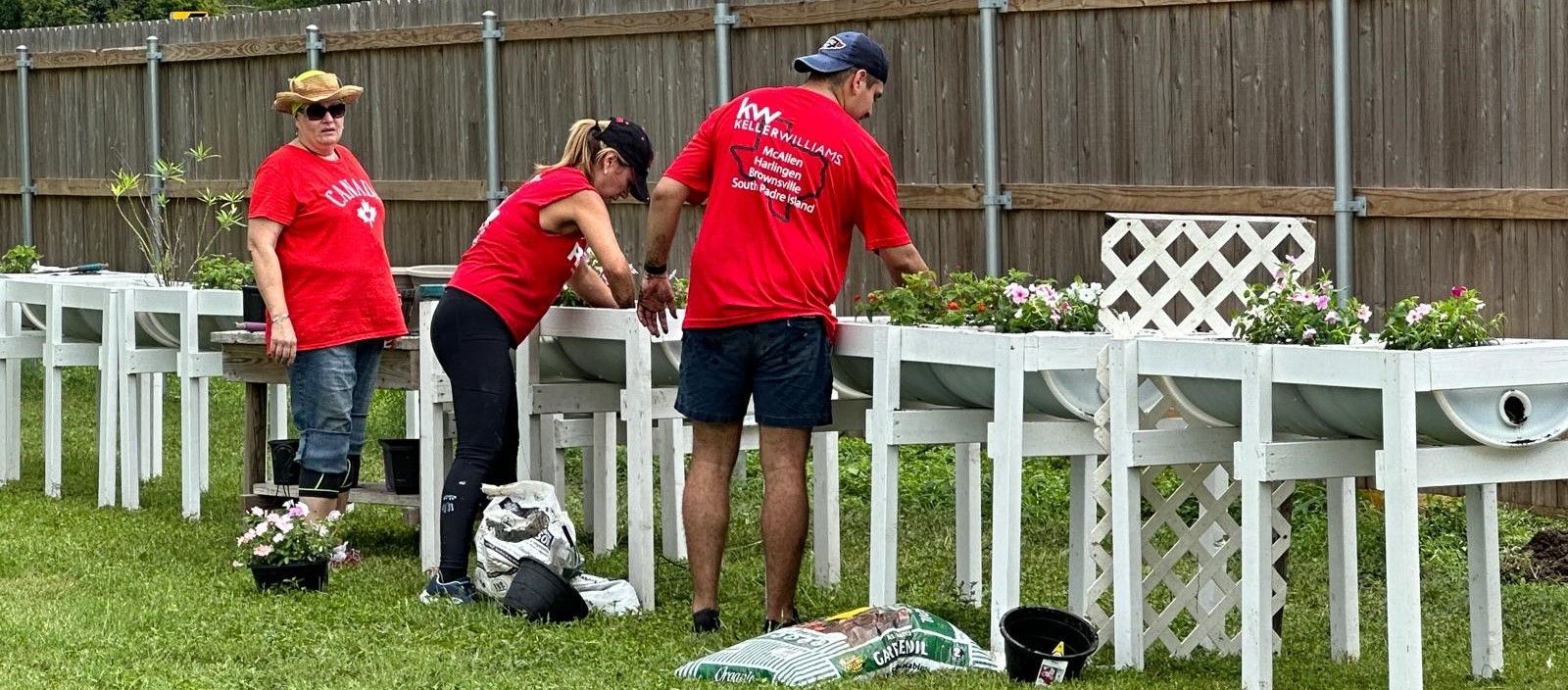 A group of people in red shirts are working in a garden.