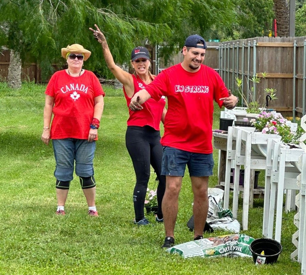 A group of people in red shirts are standing in a grassy field.