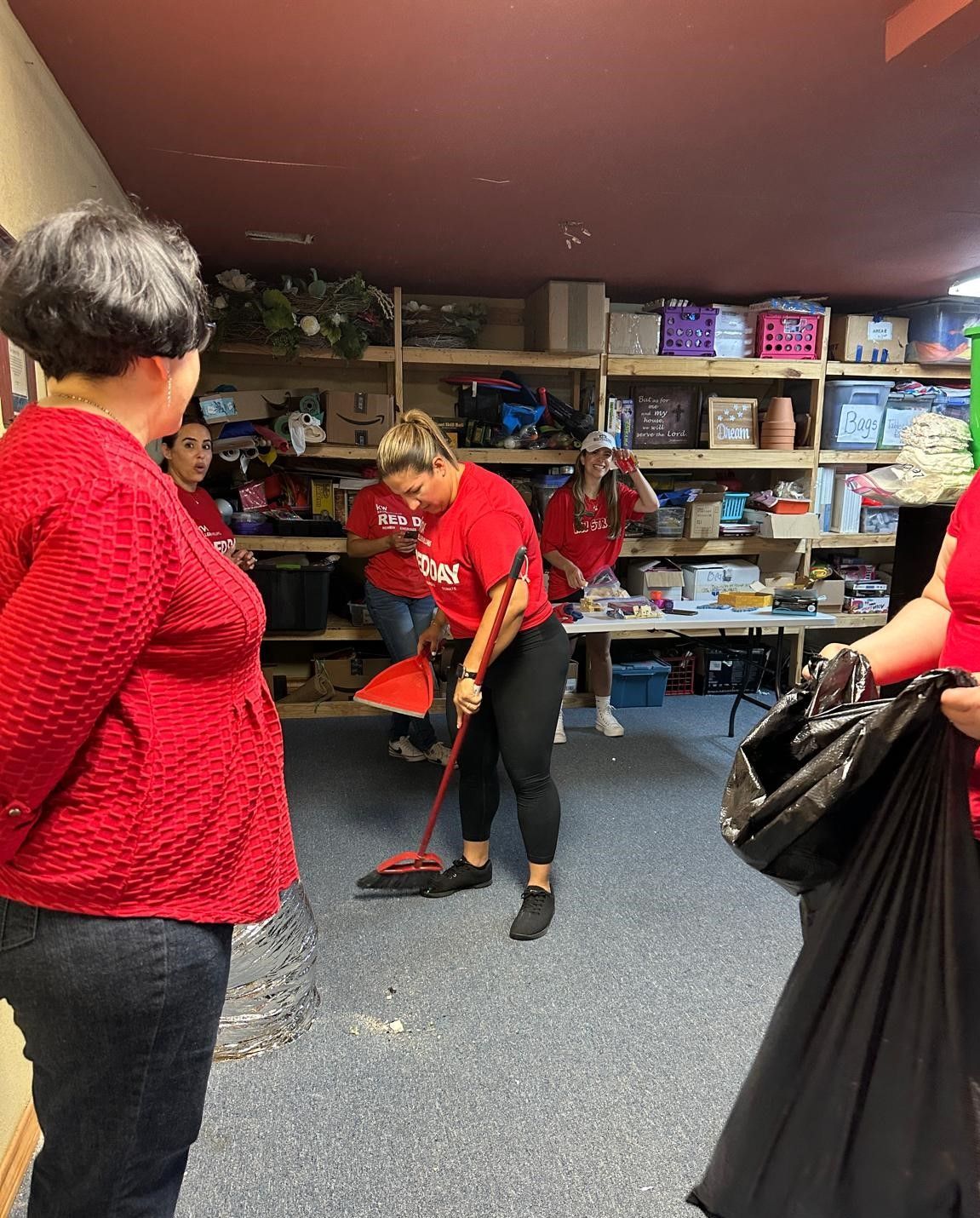 A woman in a red shirt is sweeping the floor