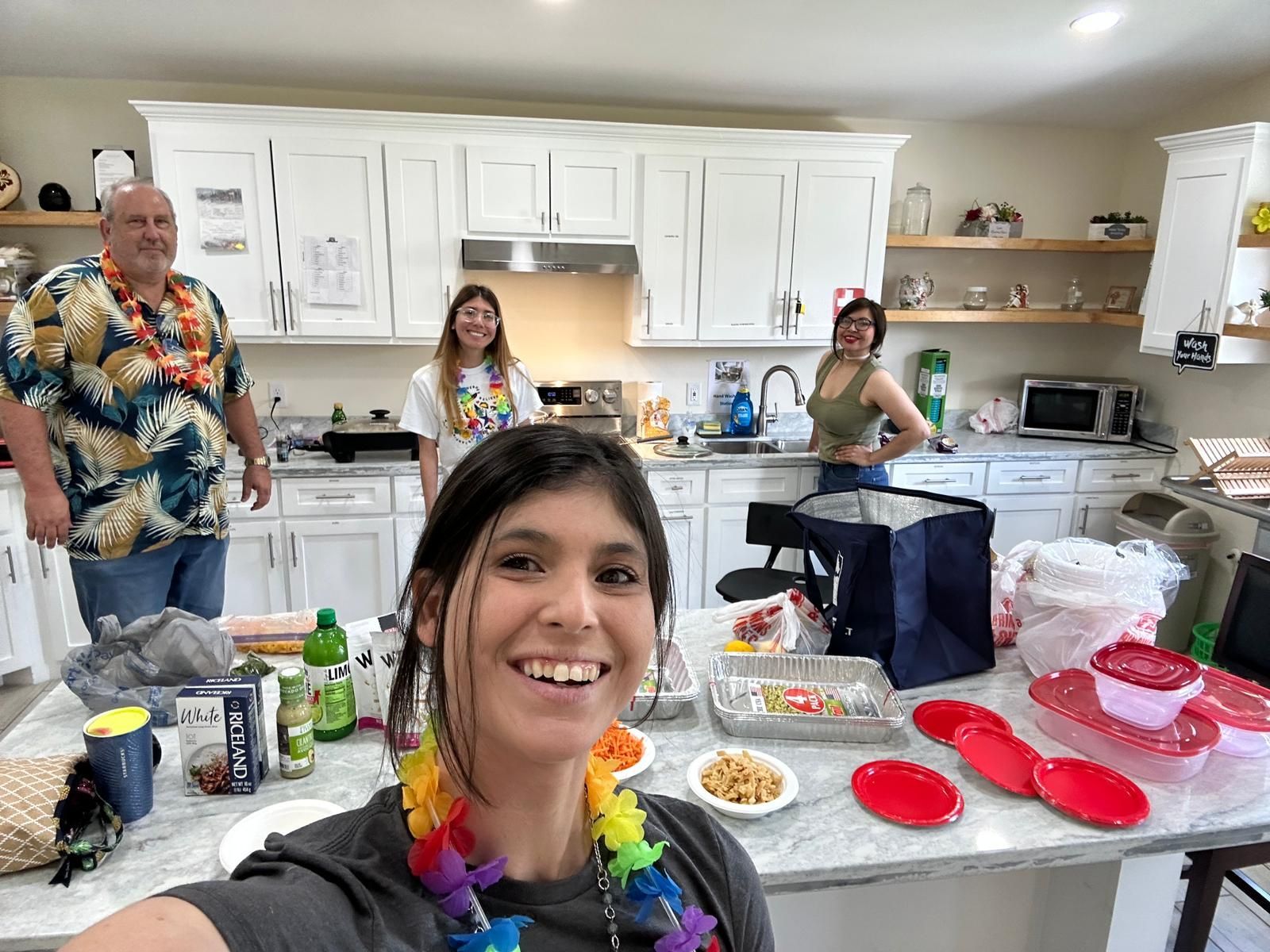 A woman is taking a selfie in a kitchen with her family.