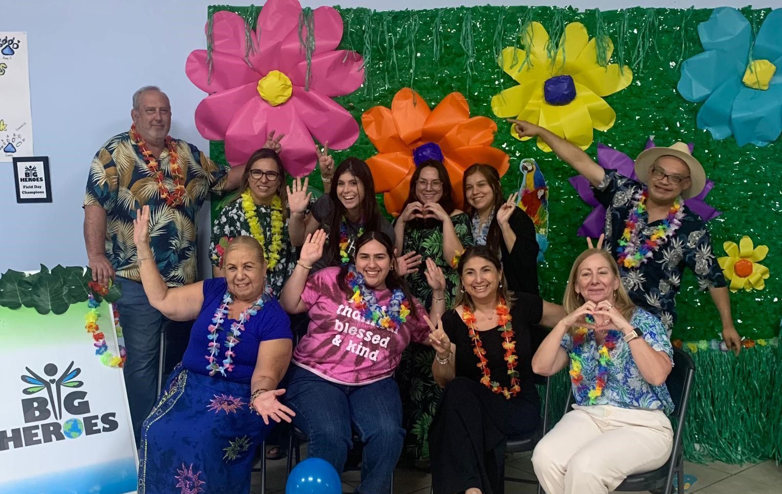 A group of people wearing hawaiian shirts are posing for a picture.