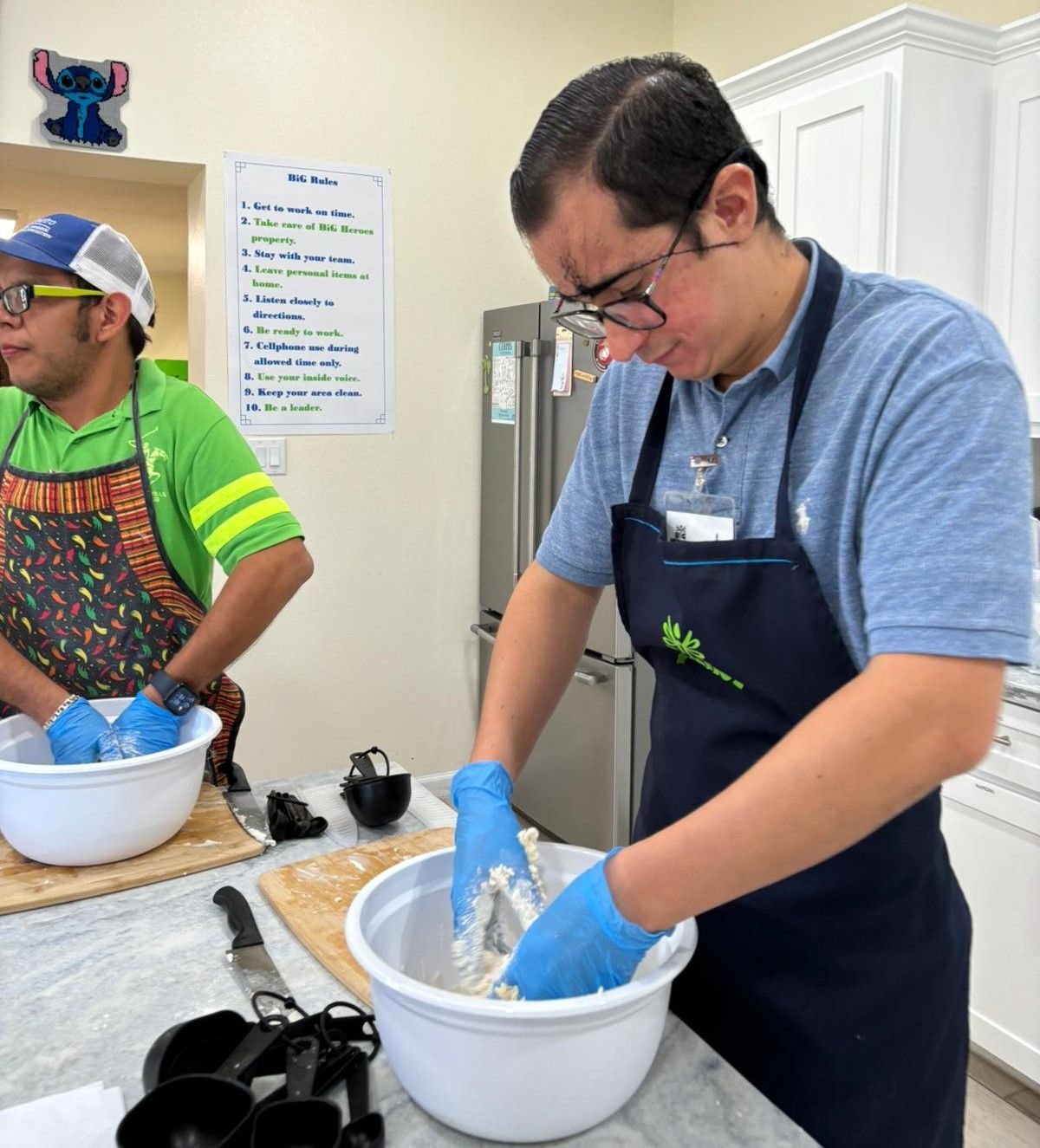 Two men in aprons are preparing food in a kitchen