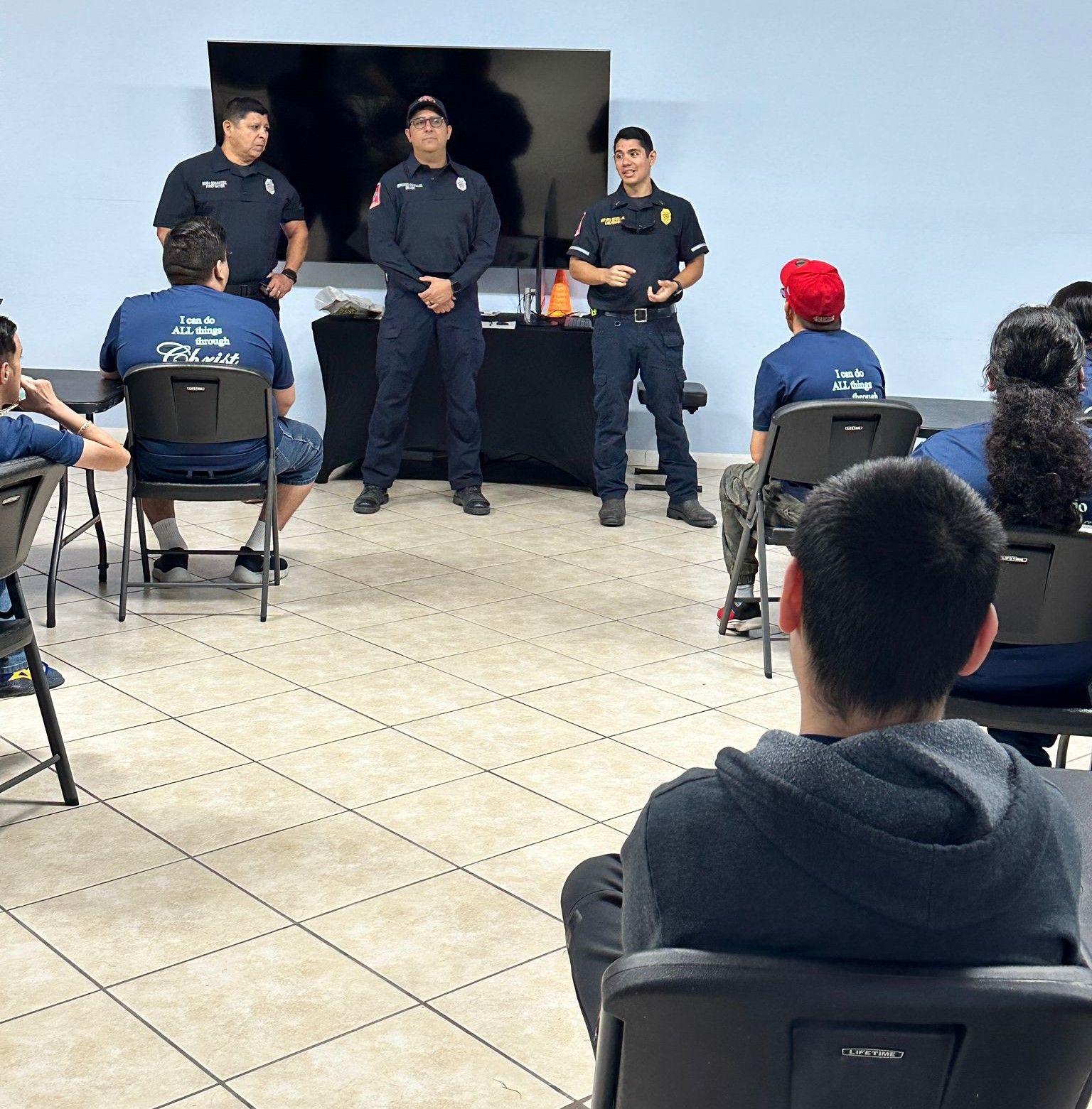 A group of people sitting in chairs and standing in a room