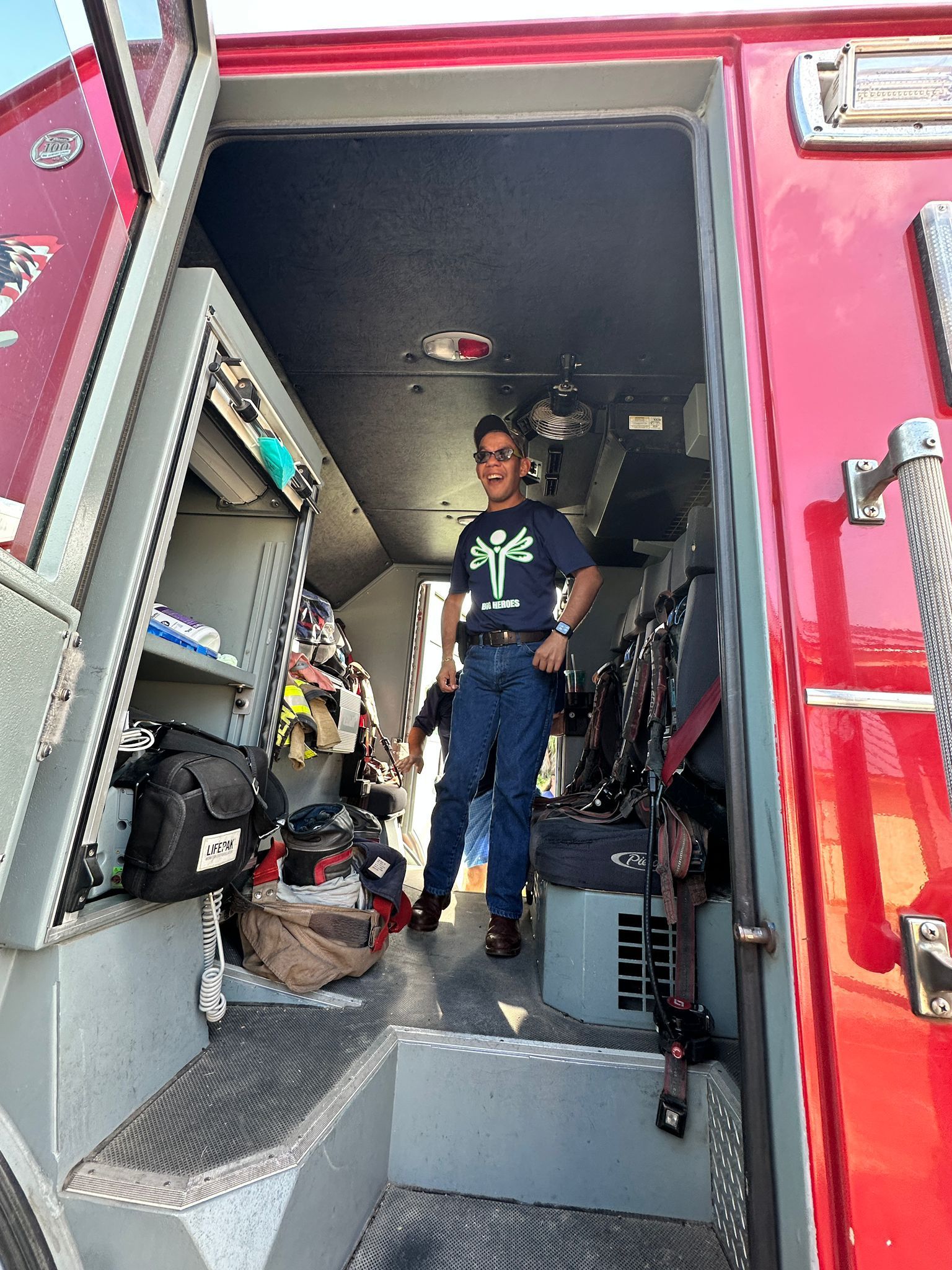 A man is standing inside of a red fire truck.