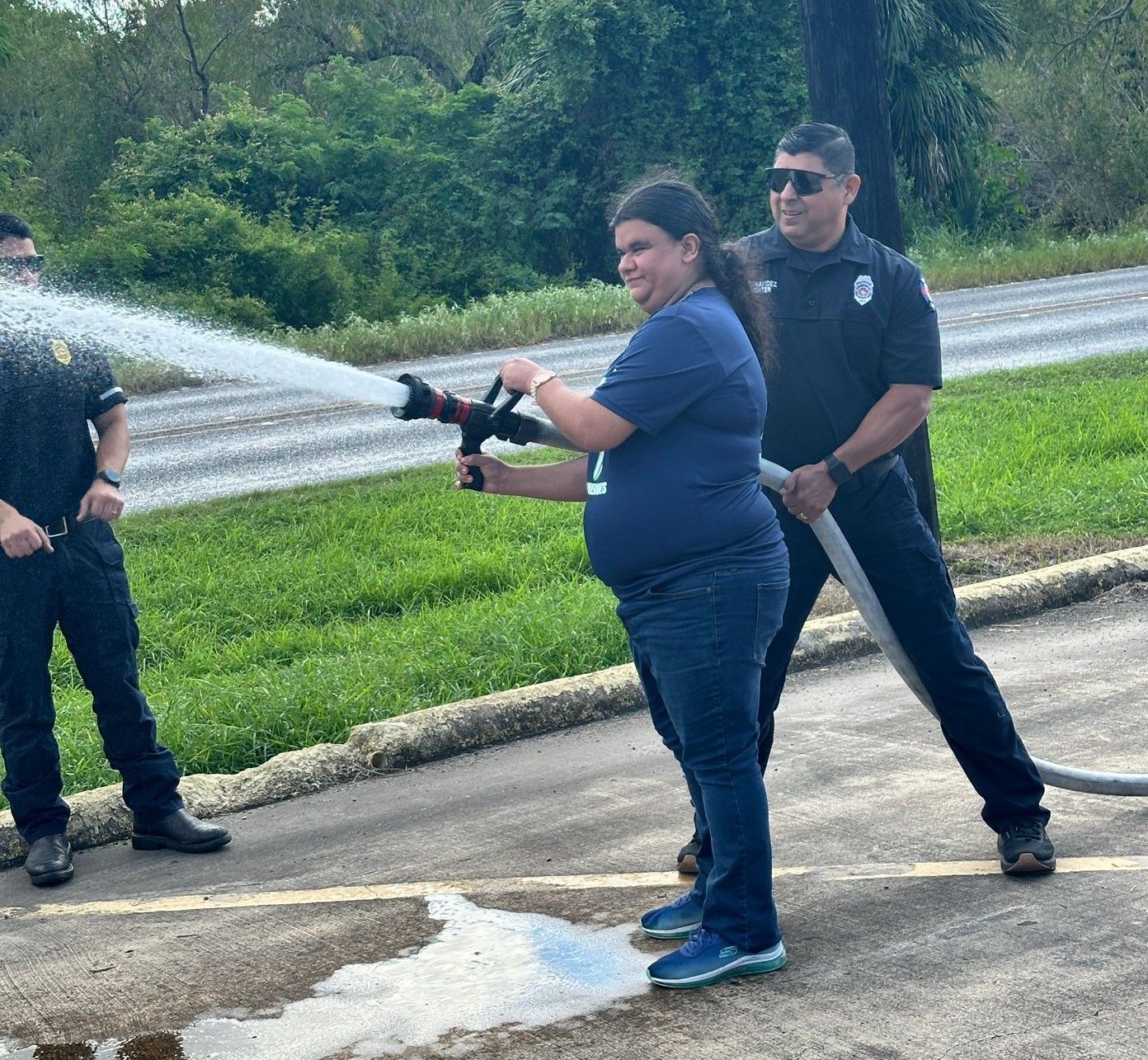 A man and a woman are spraying water from a fire hose.