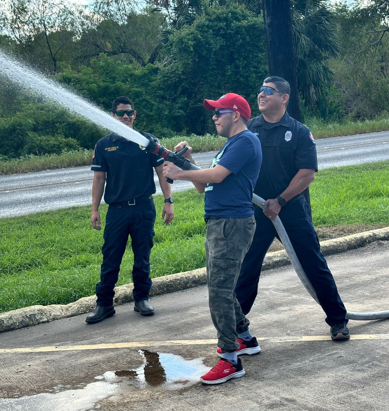 A man in a red hat is spraying water from a fire hose