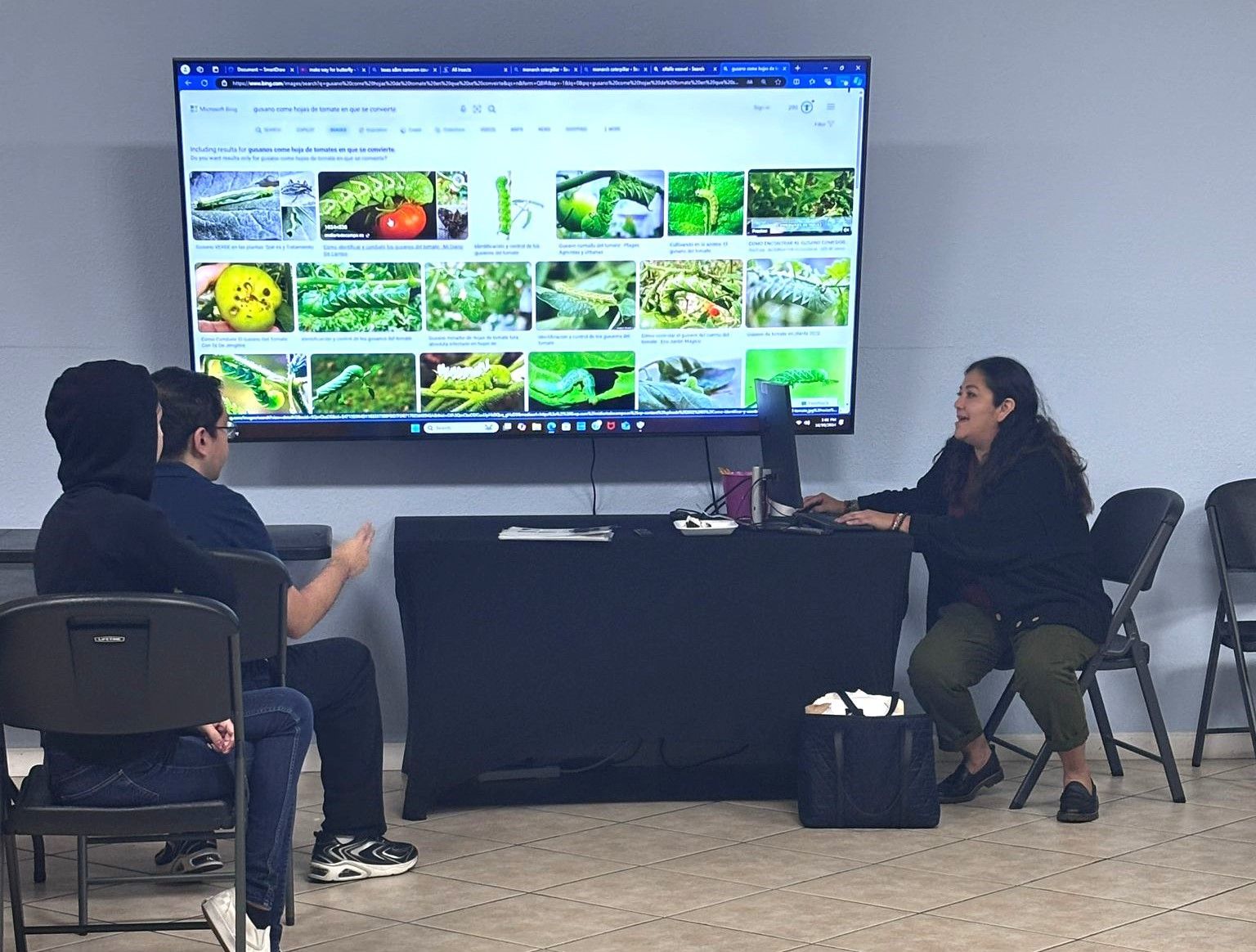 A group of people are sitting in front of a large flat screen tv.
