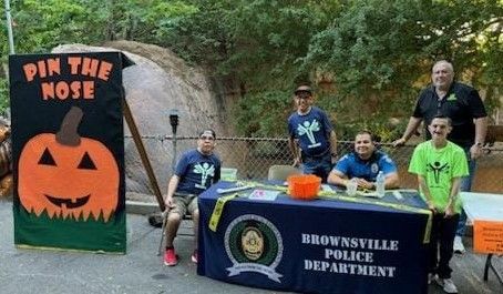 A group of people standing around a table with a pumpkin on it.