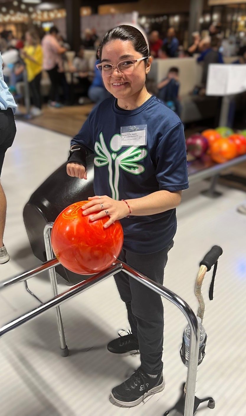 A woman is holding a bowling ball in a bowling alley.