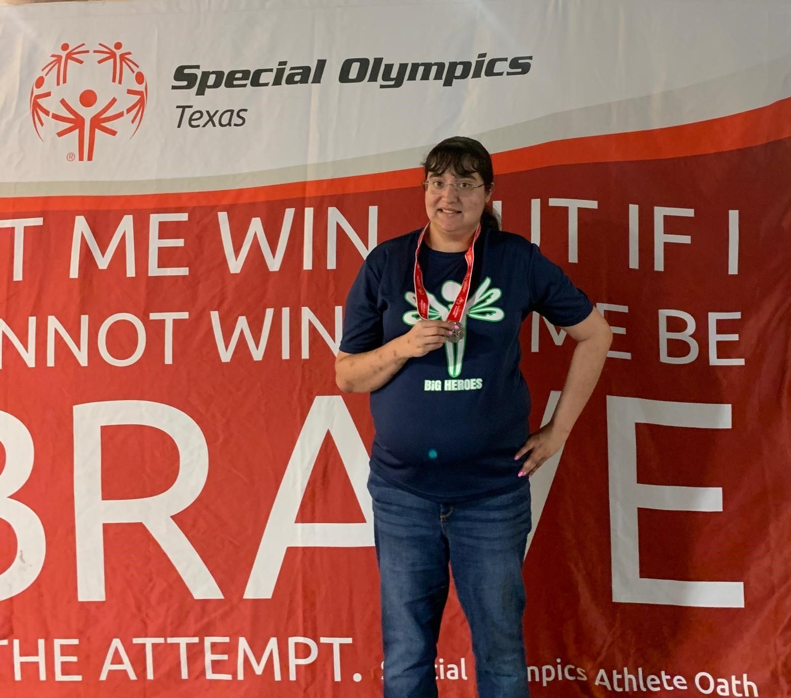 A woman stands in front of a special olympics texas banner