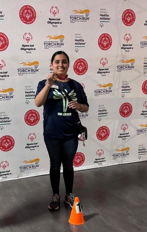 A woman is standing in front of a wall holding a medal.