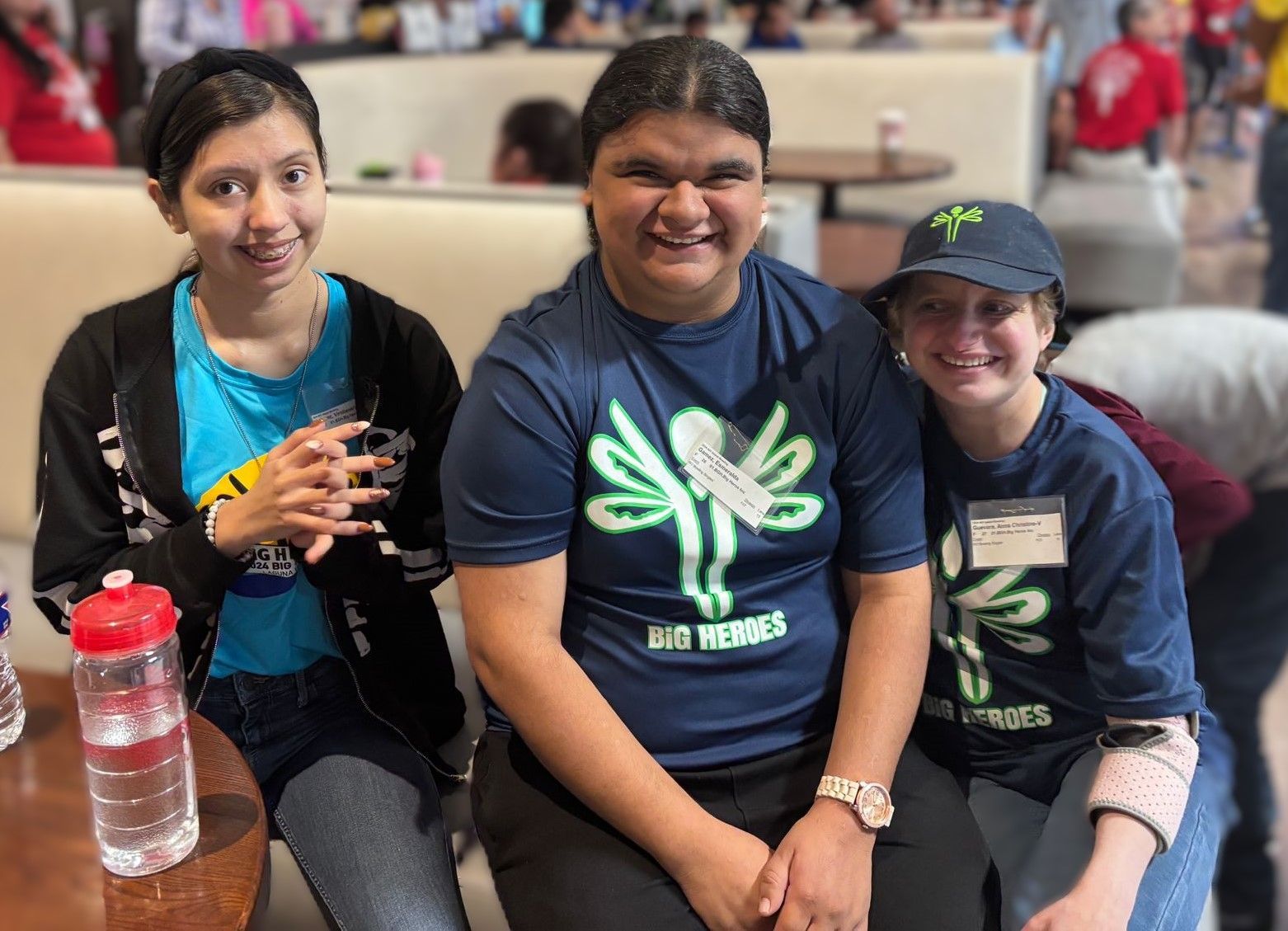 Three girls are posing for a picture while sitting at a table.