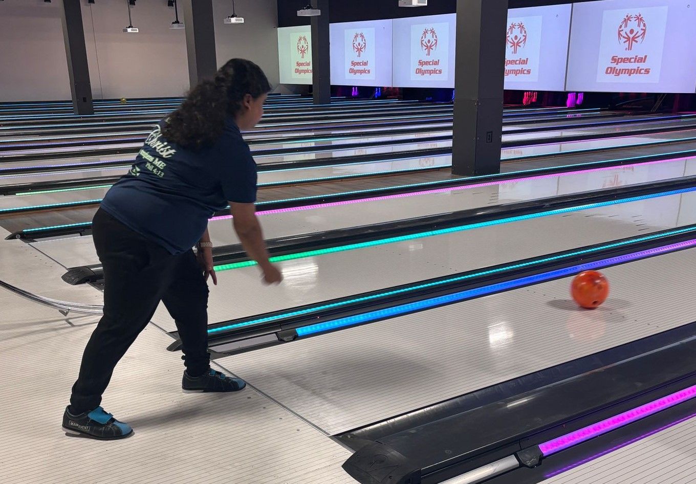 A woman is throwing a bowling ball on a bowling alley.