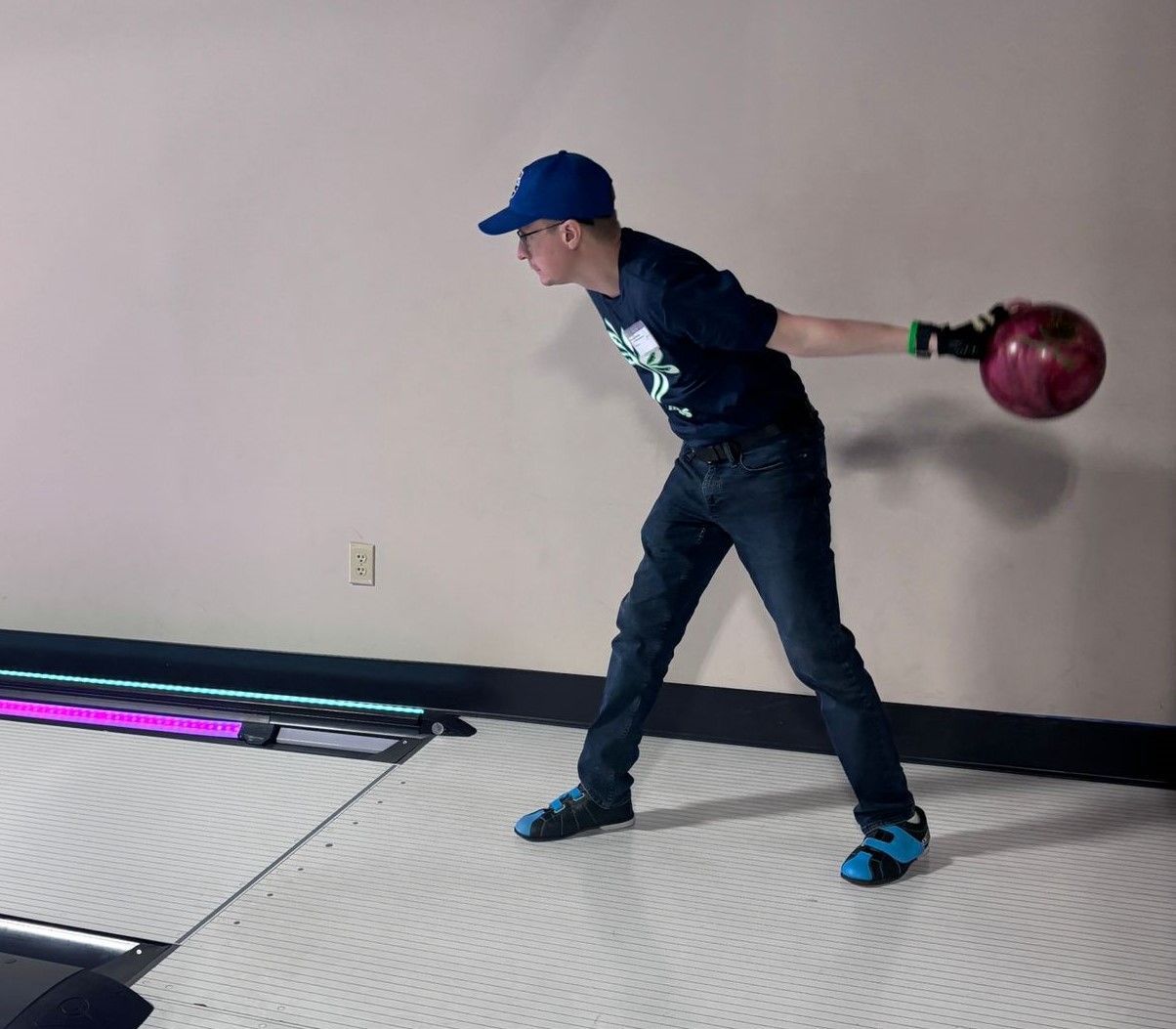 A man in a blue hat is throwing a bowling ball