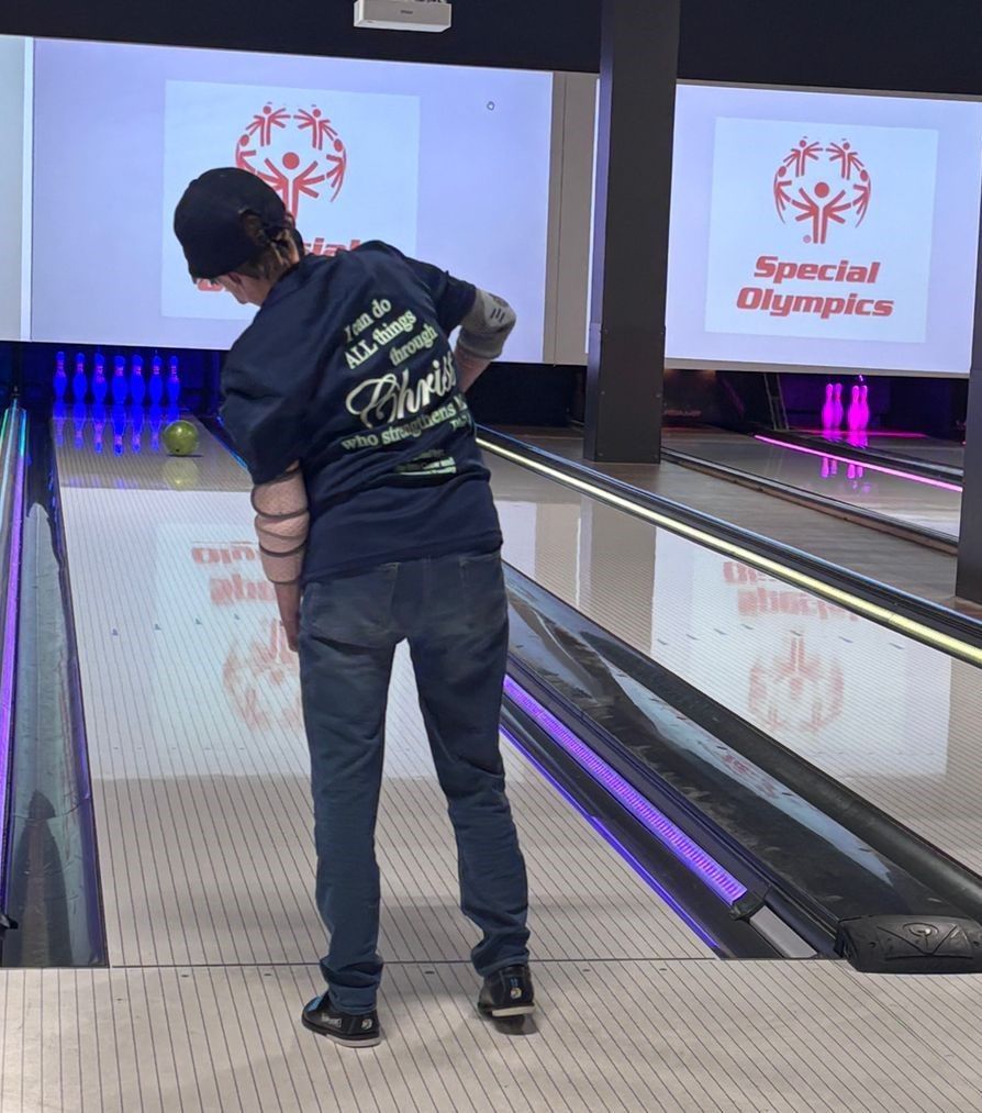 A man is playing bowling in a special olympics bowling alley
