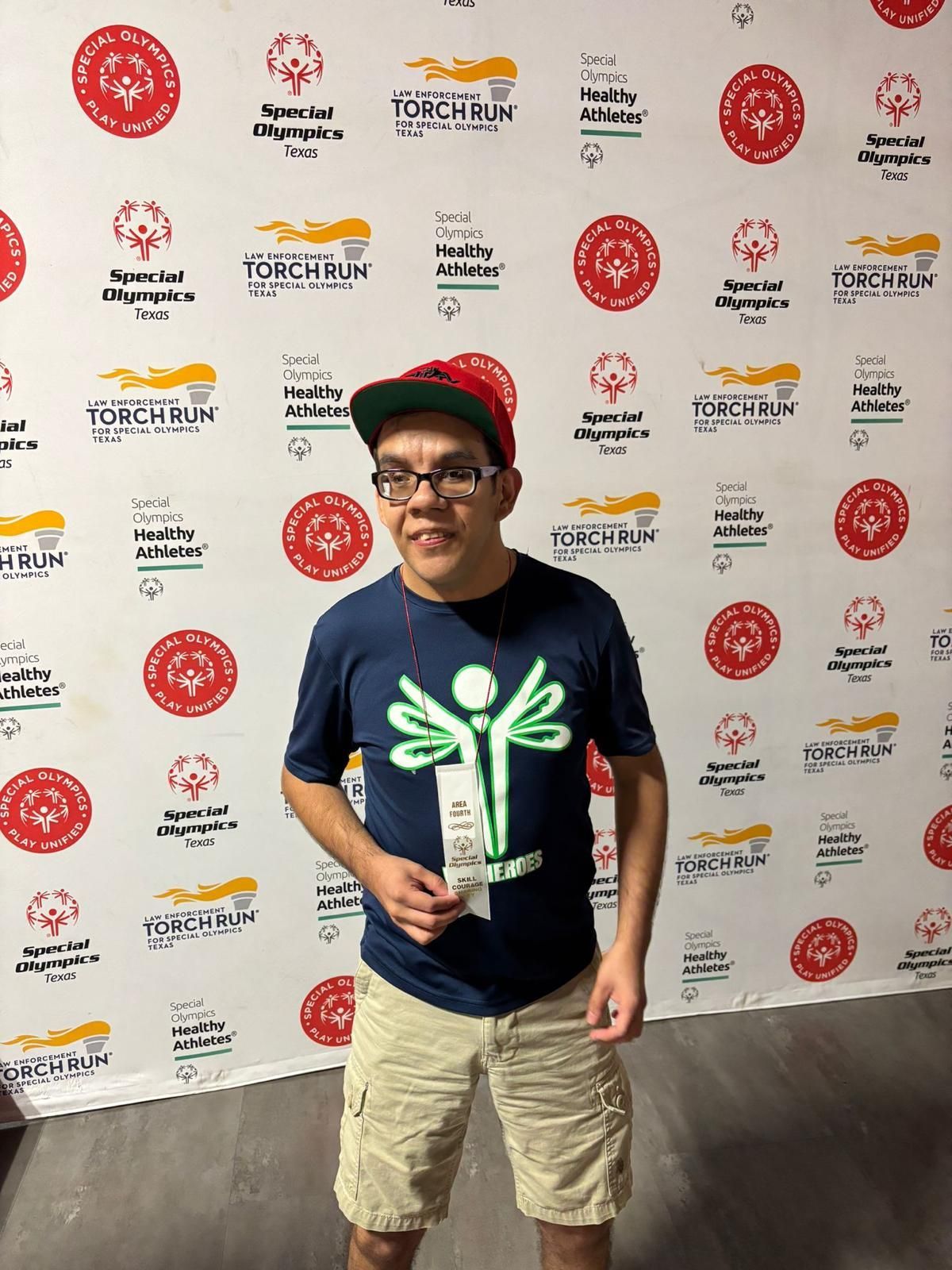 A man wearing glasses and a hat is standing in front of a wall with logos on it.
