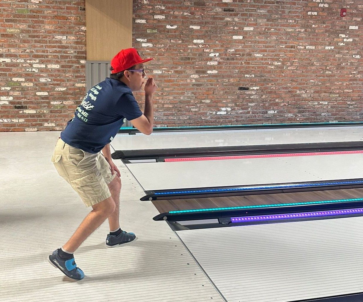 A man in a blue shirt and red hat is standing on a trampoline.