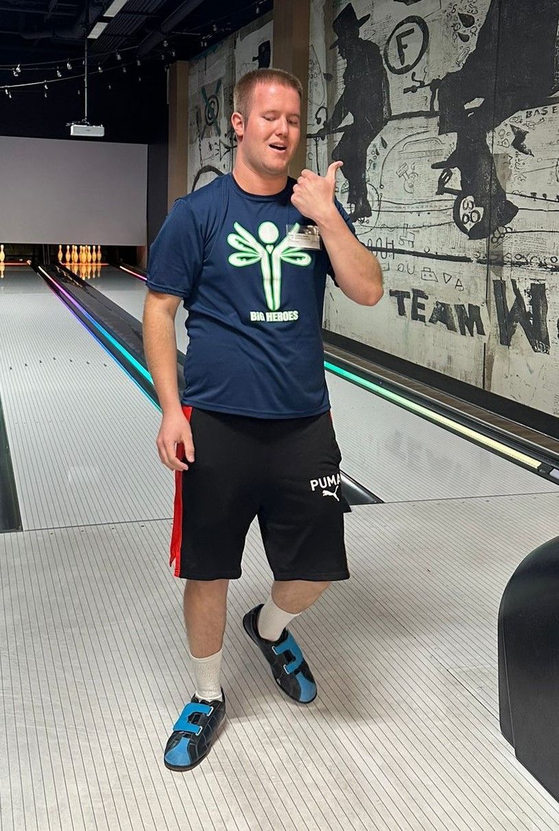 A man in a blue shirt is standing on a bowling alley.