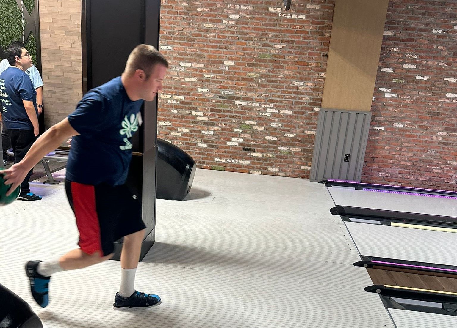 A man is throwing a bowling ball in a bowling alley.