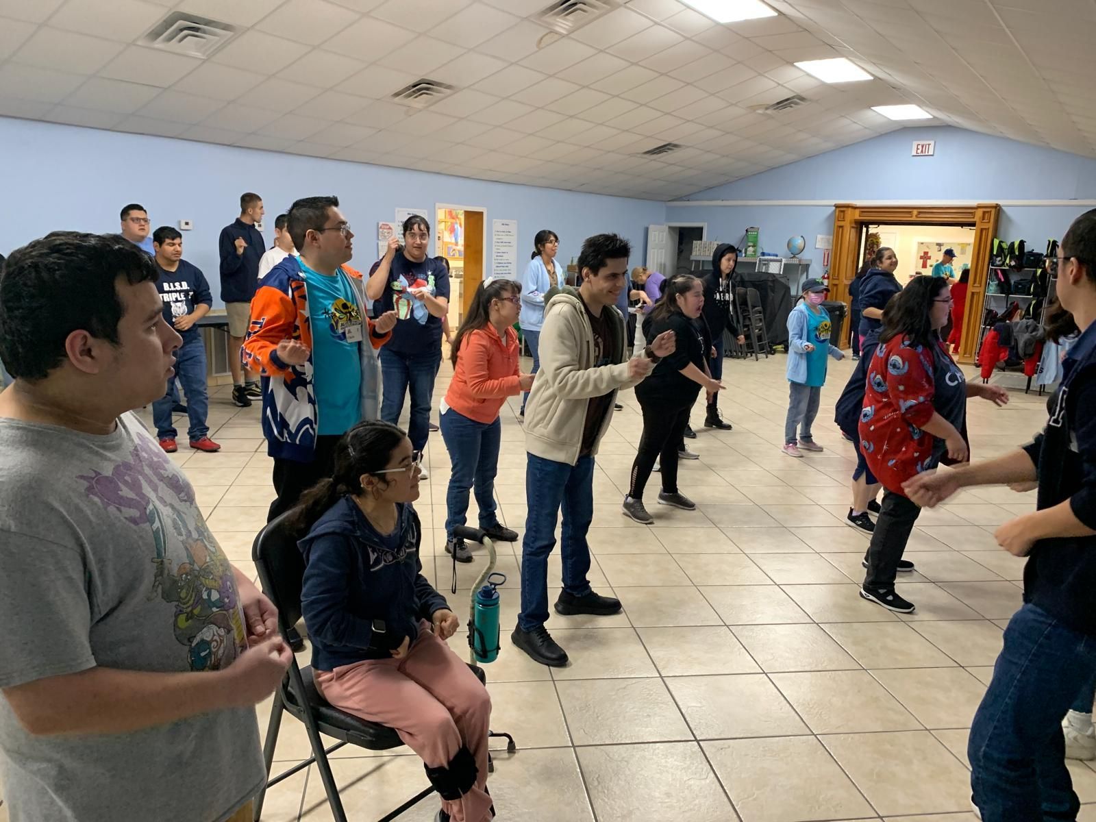 A group of people are standing and dancing in a room.