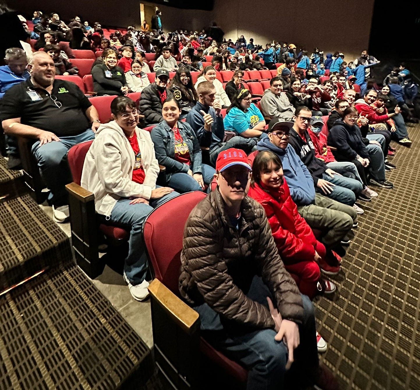 A large group of people are sitting in a theater watching a movie