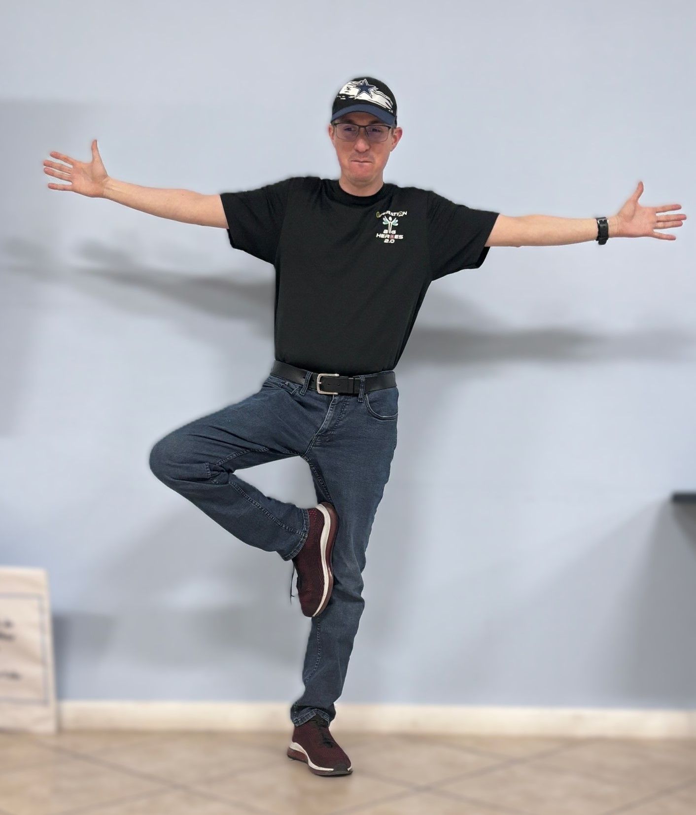 A man is standing on one leg with his arms outstretched.