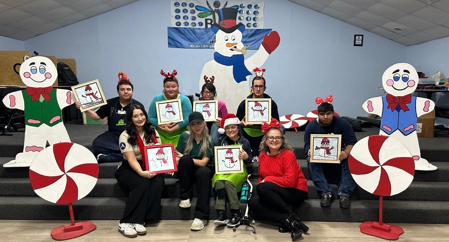 A group of people are posing for a picture in front of a snowman and candy canes.