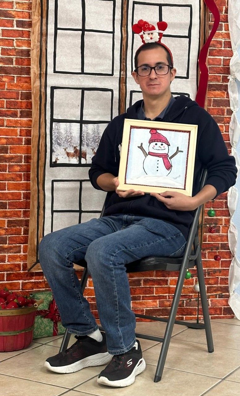 A man is sitting in a chair holding a picture of a snowman.