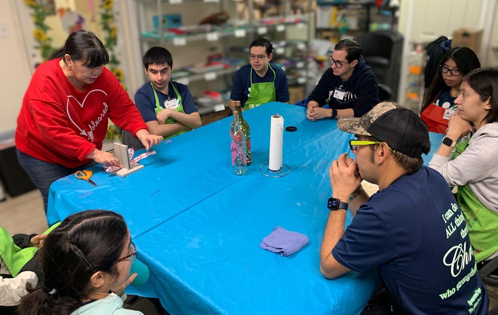A group of people are sitting around a table with a blue tablecloth.