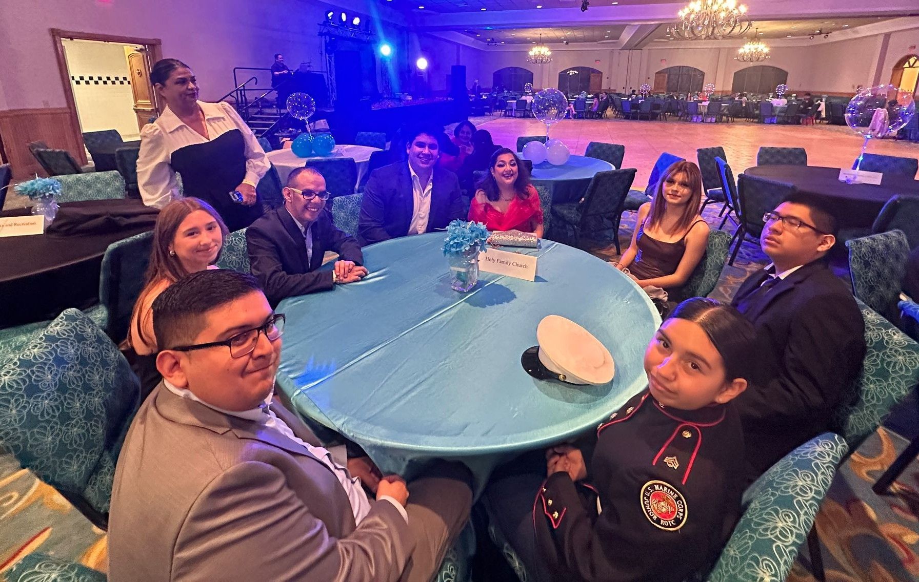 A group of people are sitting around a table in a large room.