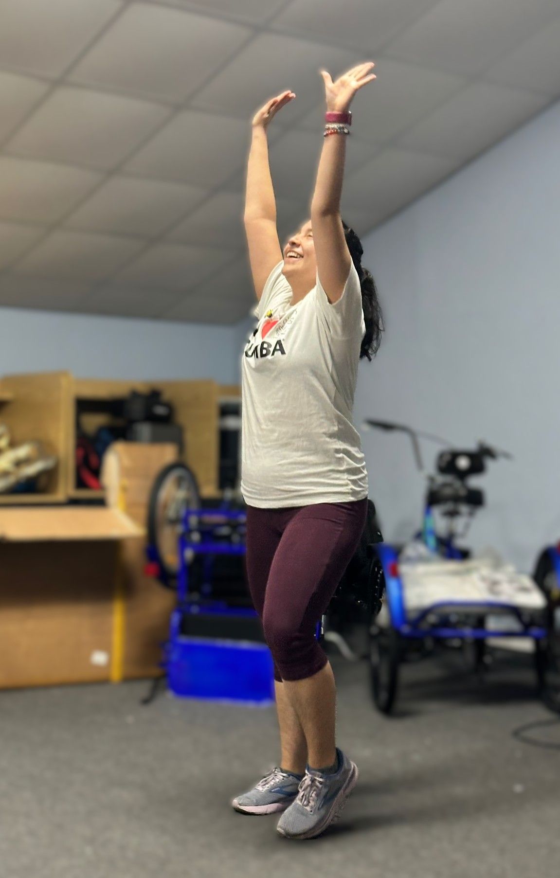 A woman is standing in a room with her arms in the air.