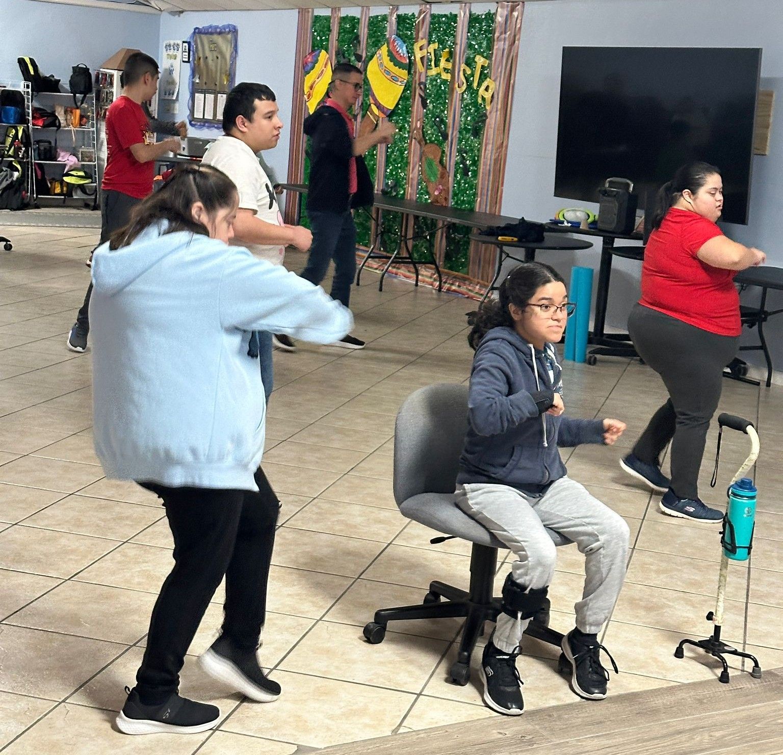A group of people are dancing in a room with a sign that says kid to