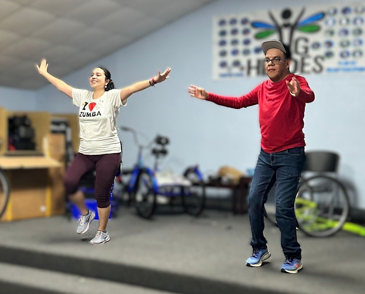 A man and a woman are dancing in front of a sign that says go heroes