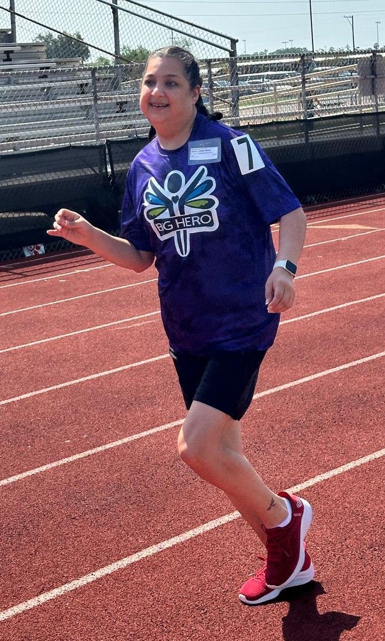 A girl in a purple shirt is running on a track.
