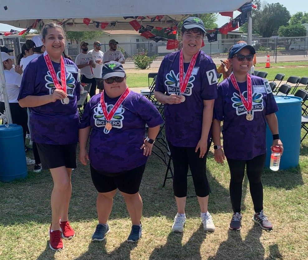 A group of women wearing purple shirts and medals are standing next to each other.