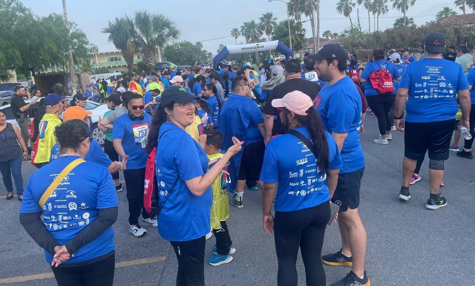 A group of people wearing blue shirts are standing on a street.