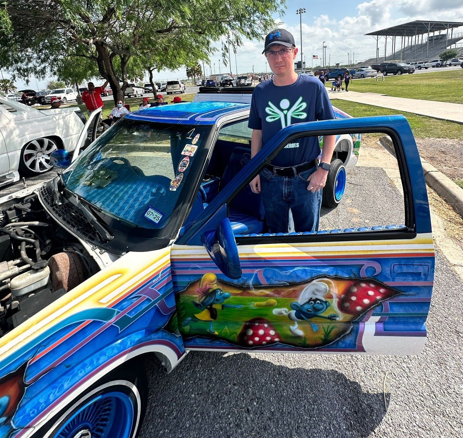 A man is standing next to a colorful car with the door open