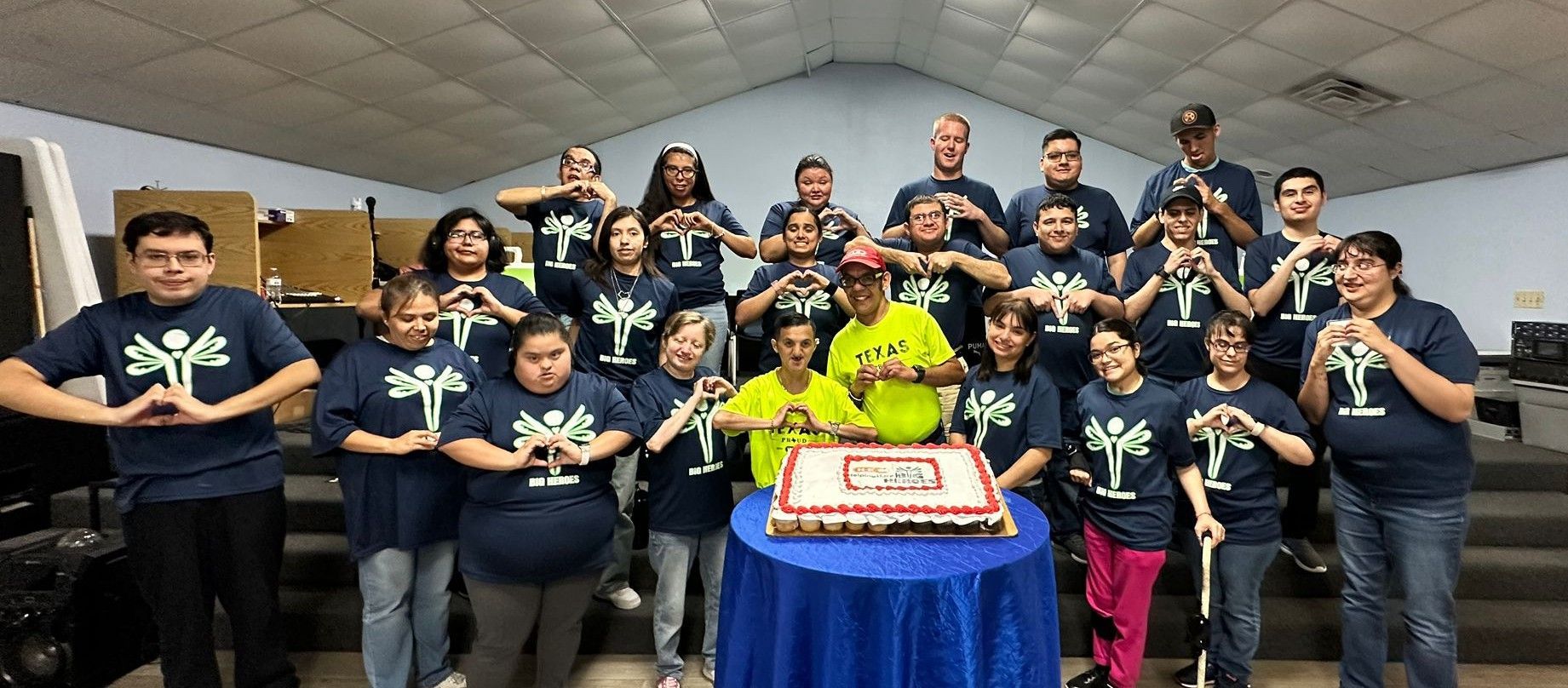 A group of people are posing for a picture in front of a cake.