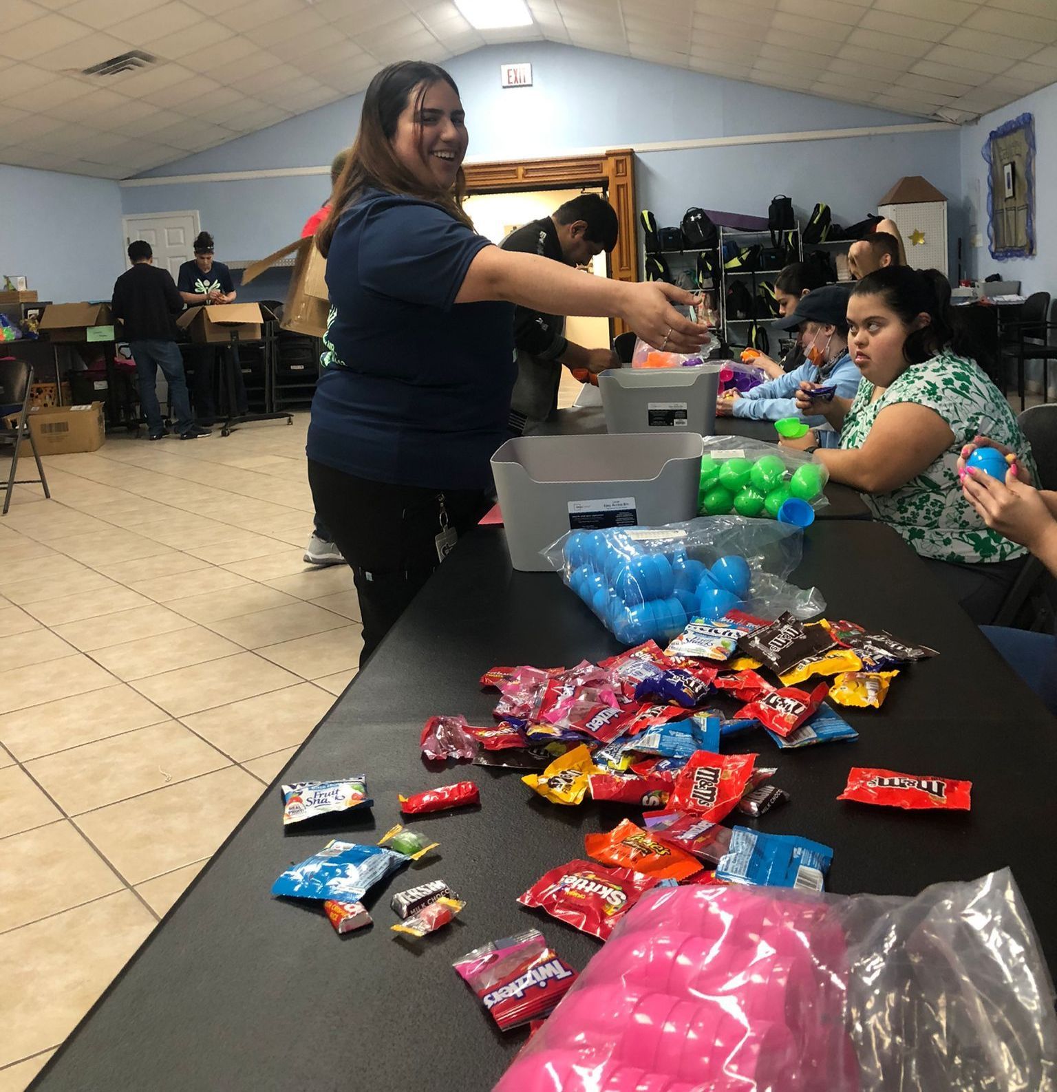 A group of people are gathered around a table filled with candy including m & m 's