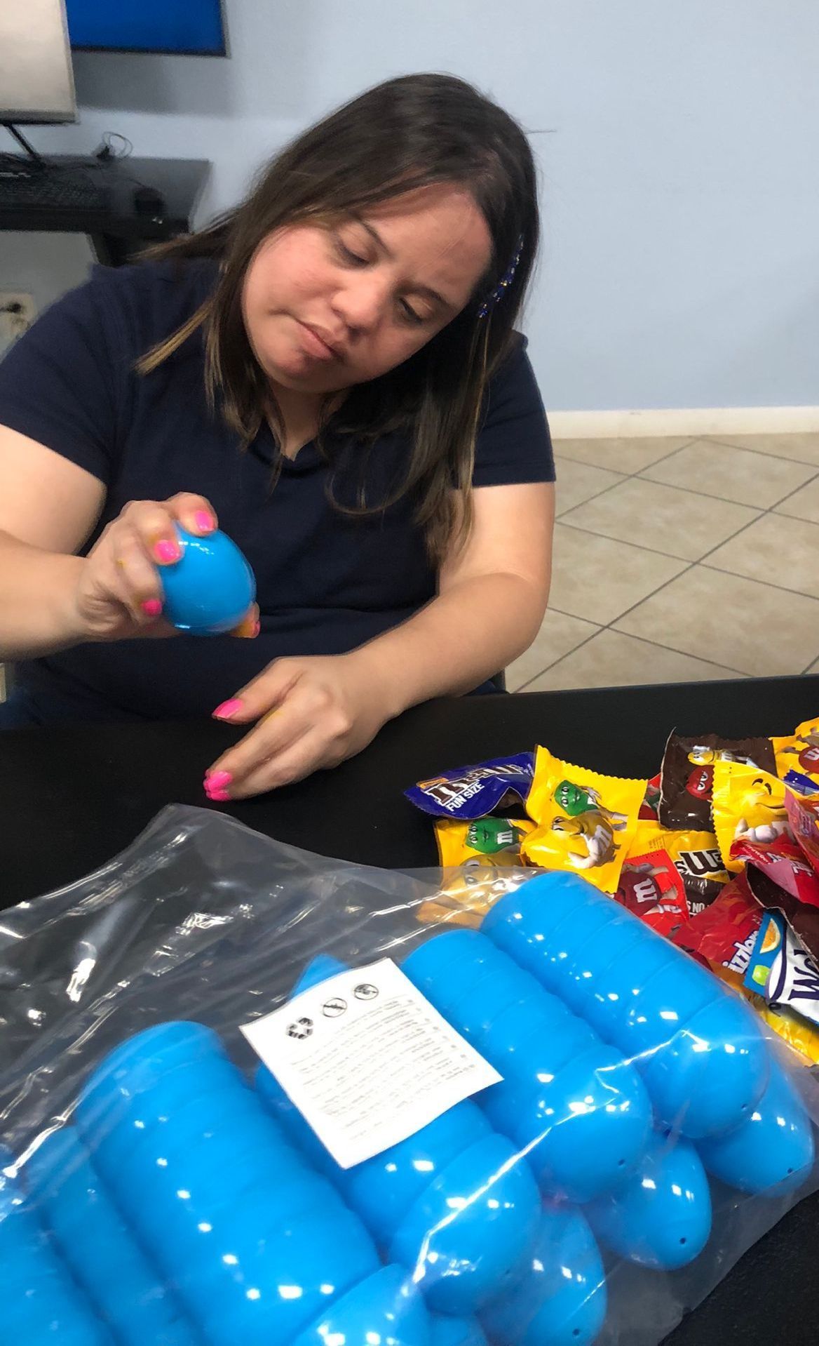 A woman is sitting at a table holding a blue ball.
