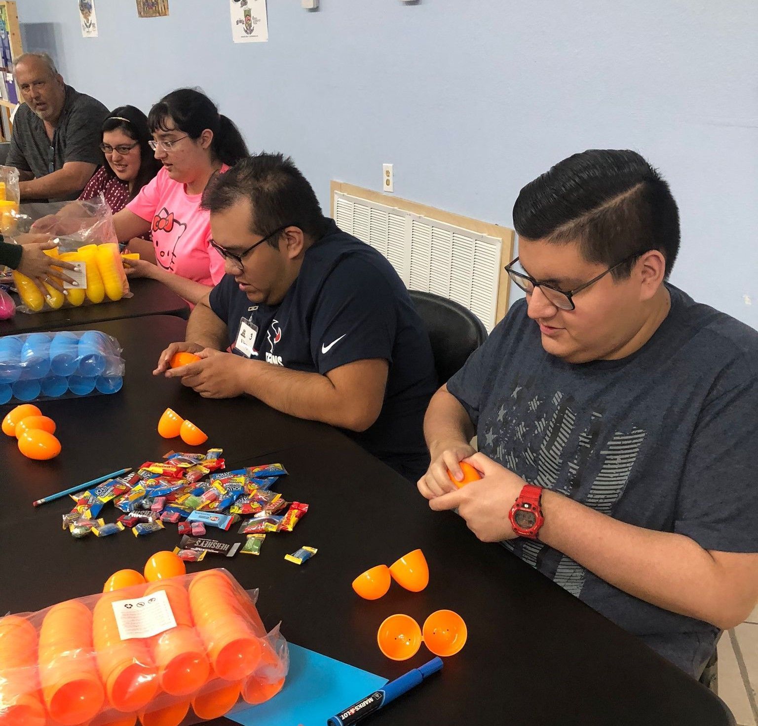 A group of people are sitting around a table making toys