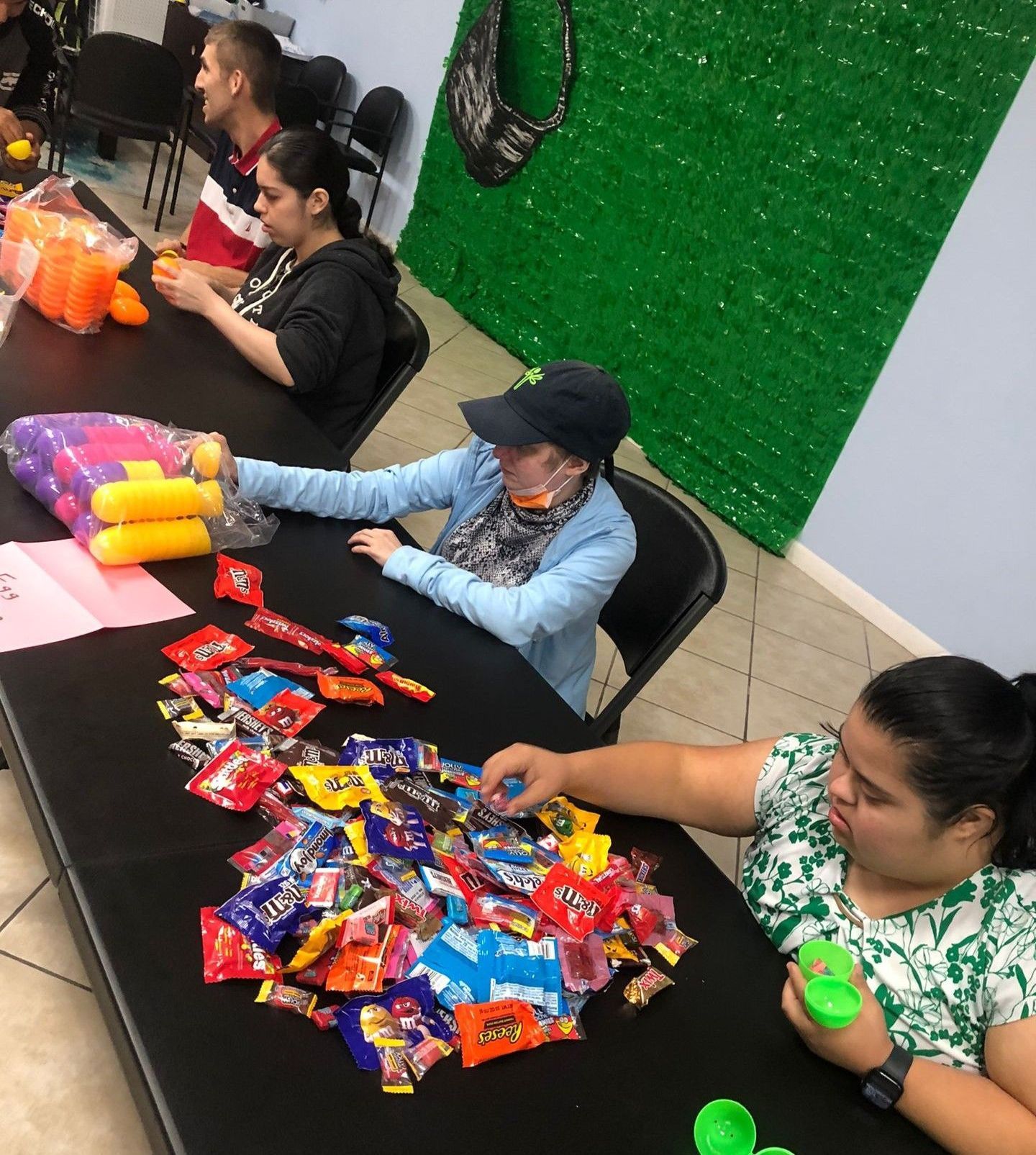 A group of people are sitting at a table with candy on it