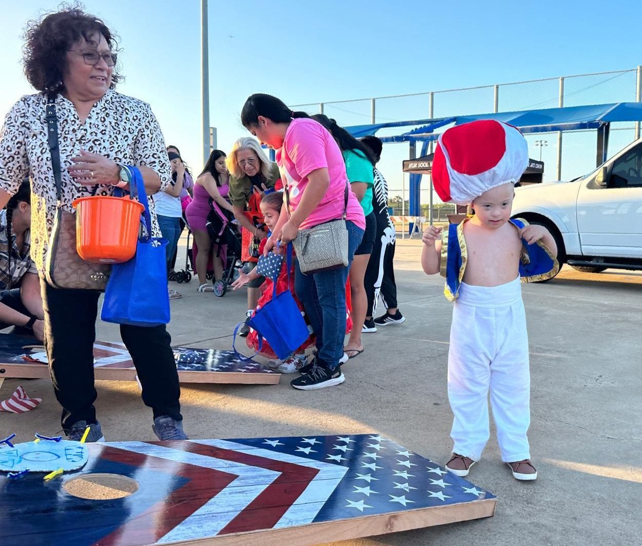 A little boy in a toad costume is standing next to a woman in a pink shirt