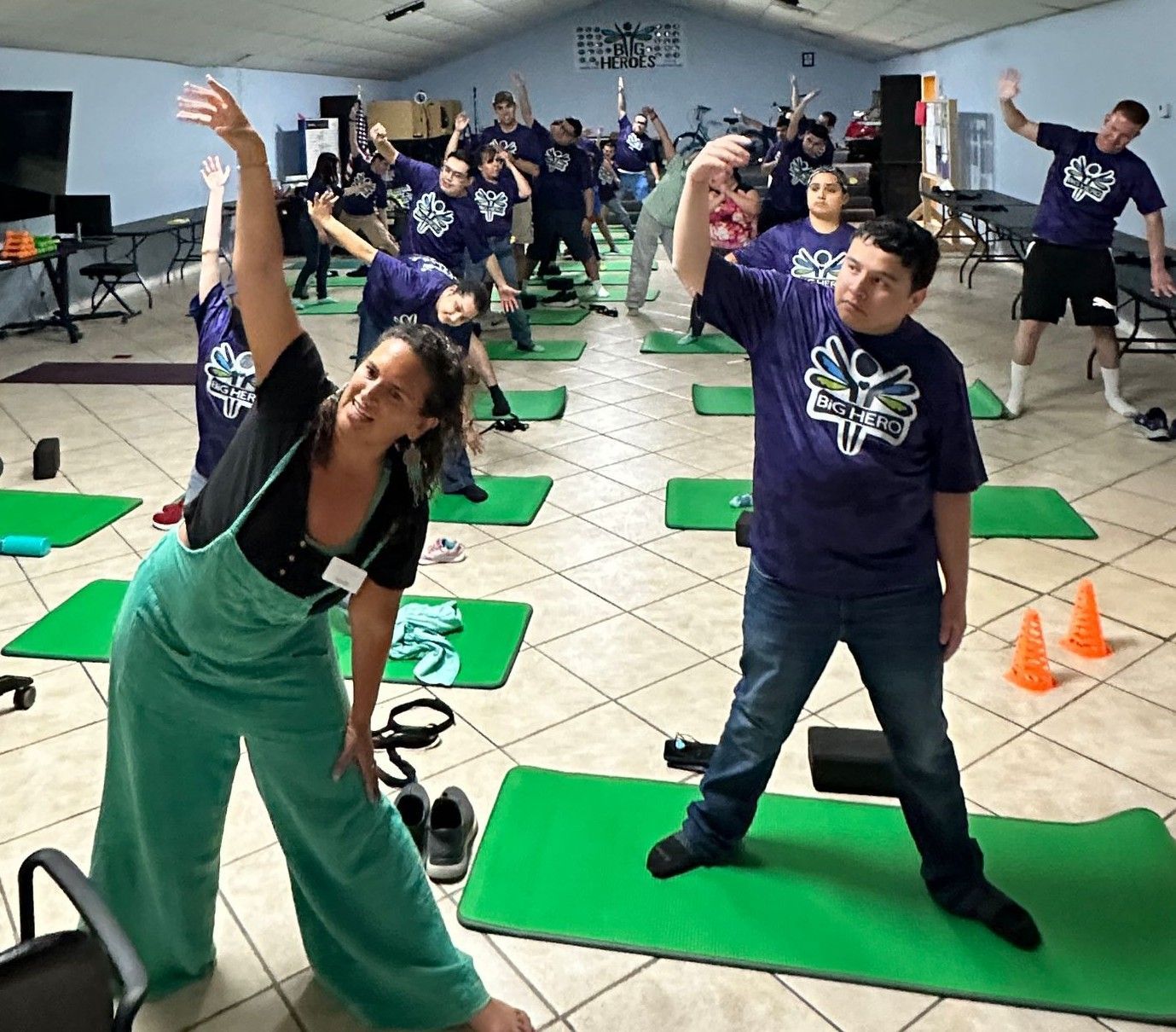 A group of people are doing stretching exercises on green mats
